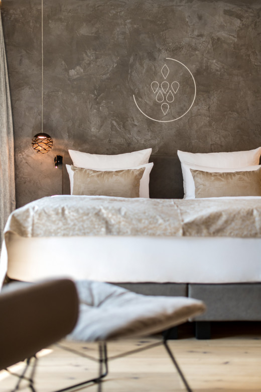 Blick auf ein Hotelbett mit Logo an der Wand