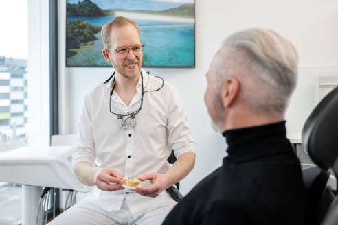 Junger Zahnarzt berät einen Patienten