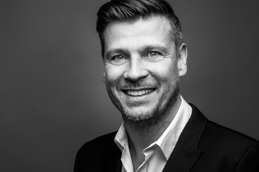 Mann lächelt für ein Bewerbungsfoto in die Kamera