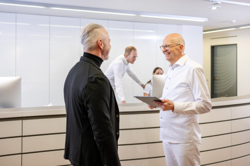 Zahnarzt spricht mit Patientin am Empfang