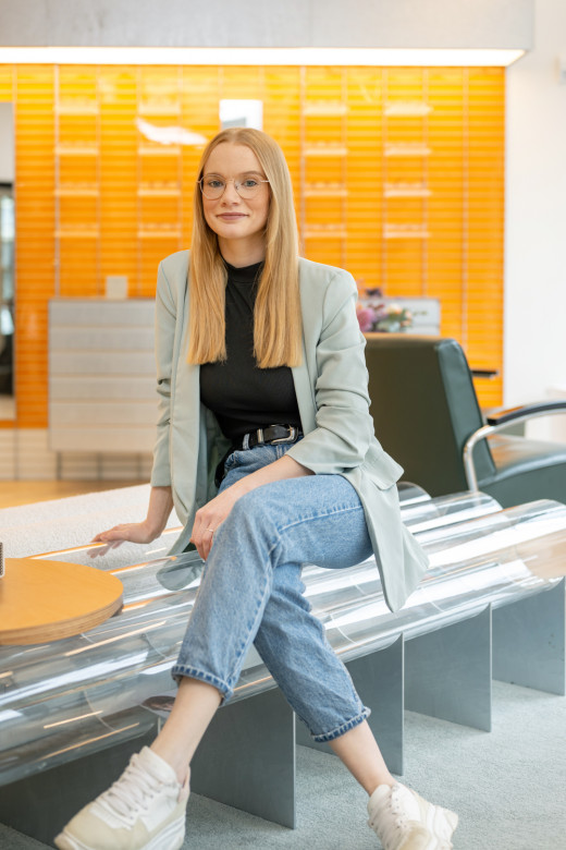 Mitarbeiterin sitzt auf einer Bank und lächelt