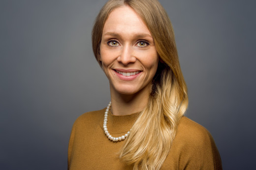 Junge Frau lächelt für ein Bewerbungsfoto in die Kamera