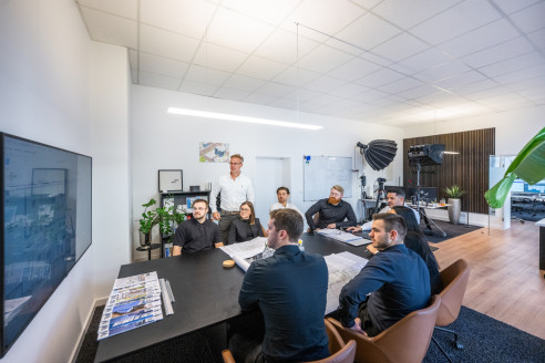 große Teambesprechung vor einen TV im Büro